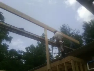 Carpenter setting a ridge beam over a new addition frame — Ice Dam Removal by Roofing Brothers in Gibson