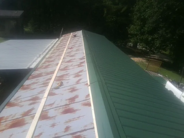 Old rusted panels beside newly installed green metal roofing — Wind Damage Roof Repair by Roofing Brothers in Gibson