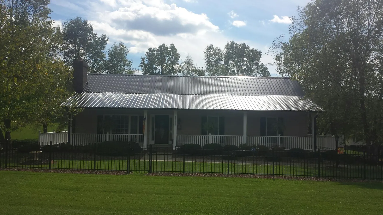 Gray metal roof on a brick ranch with a full width front porch — Gutter Guard Installation work by our crew in Gibson
