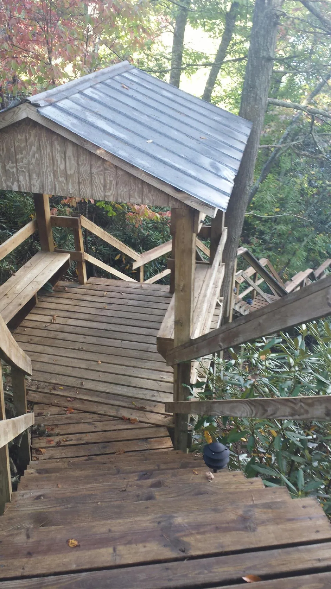 Metal roofed shelter over wooden steps on a wooded walkway — Skylight Repair & Installation work by our crew in Gibson